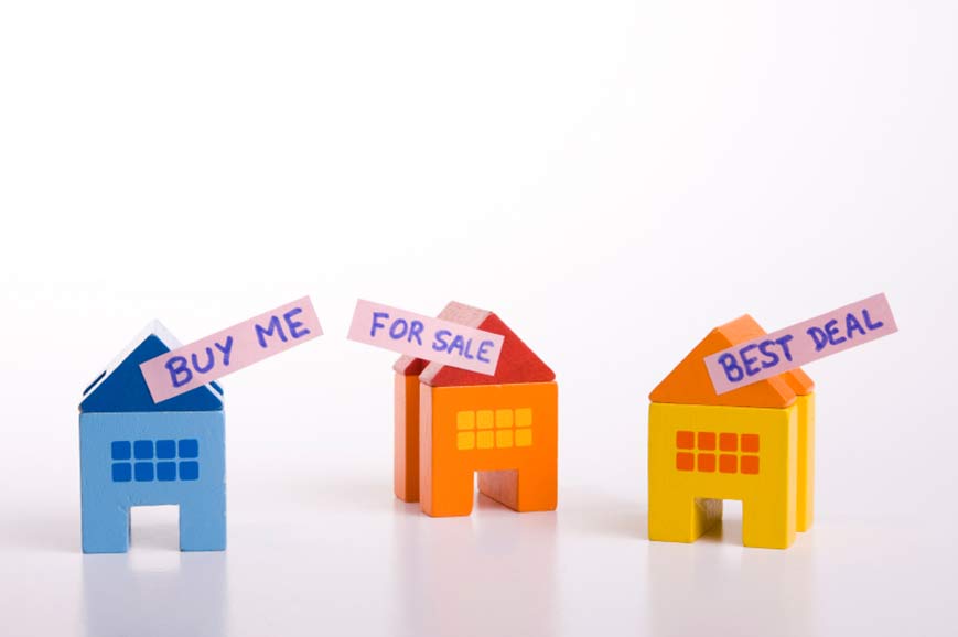 Three model houses with signs on which say: 'Buy me', 'For sale', 'Best deal'