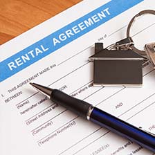 Rental agreement to be signed with a blue pen and house shaped decorative key ring