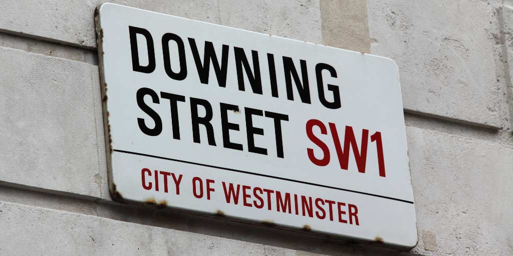 Downing Street sign on white brick wall
