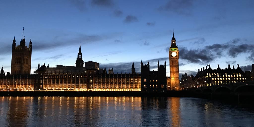 Houses of Parliament, Big Ben at dusk with lights reflecting on Thames river in foreground