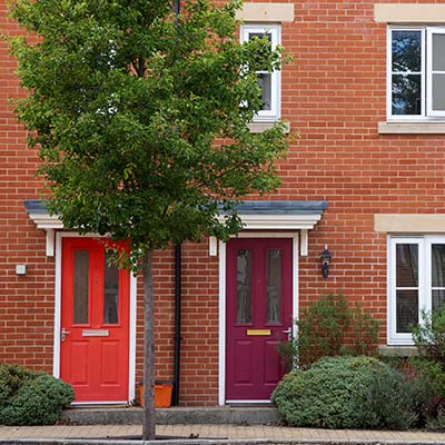 Modern residential terraced houses with red an mauve windowed front doors