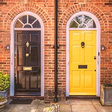 Two residential front doors. A black door on the right, bright yellow on the left