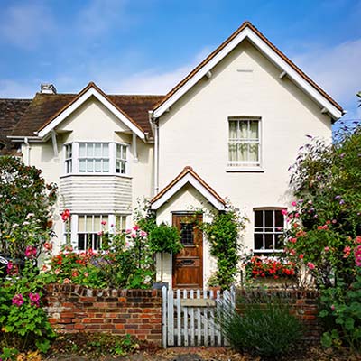 White English cottage house with traditional wooden front door and garden