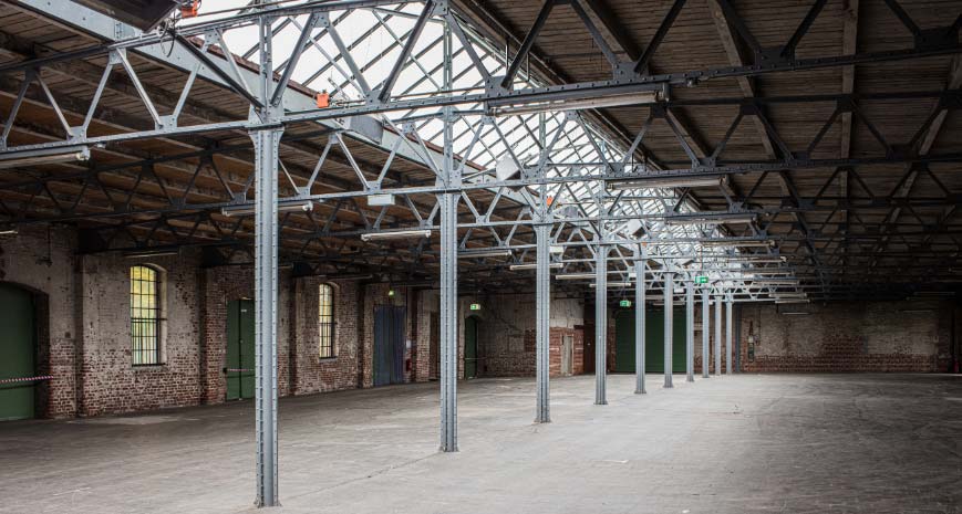 Large, empty commercial building with girders supporting the metal and glass roof