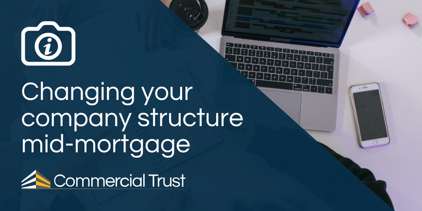 Blue banners with text "Changing your company structure mid-mortgage" and behind it a desk with a laptop and mobile phone on it