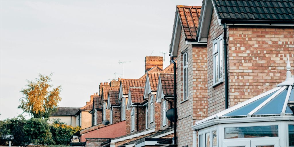 Side view of the back of several houses looking towards a tree