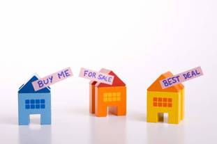 Three model houses with signs on which say: 'Buy me', 'For sale', 'Best deal'
